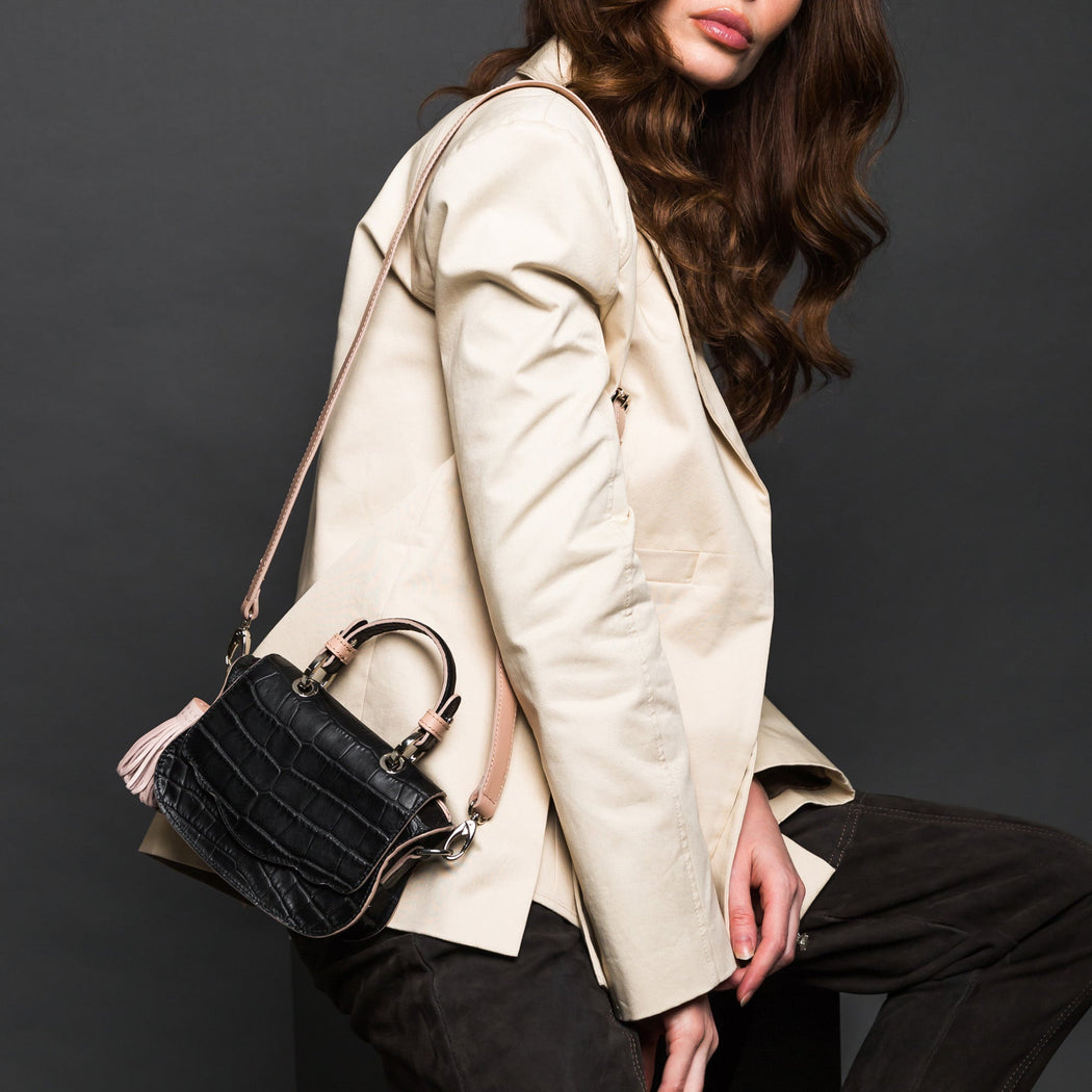 Woman wearing designer shoulder bag with croc-embossed leather